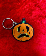 Load image into Gallery viewer, Crying pumpkin keychain in orange and black  on top of a red velvet fabric. 