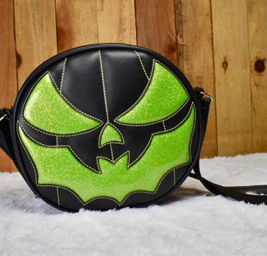 Bat mouth pumpkin bag in Black and Green glitter . Photographed on white fur against wood wall. 