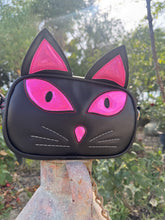 Load image into Gallery viewer, Black cat-shaped purse with pink eyes on a metal jug outdoors