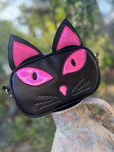 Load image into Gallery viewer, Black cat-shaped bag with pink accents on a rustic metal surface