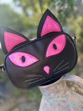 Load image into Gallery viewer, Black cat-shaped bag with pink accents on a blurred natural background