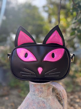 Load image into Gallery viewer, Black cat-shaped bag with pink accents on a blurred natural background