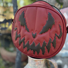 Load image into Gallery viewer, Wine Colored Vinyl bag with black design on top of a rusty metal object in a cemetery setting