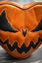 Load image into Gallery viewer, Heart shaped bag with Orange Glitter with a plain black Evil face. Close up of the face. 