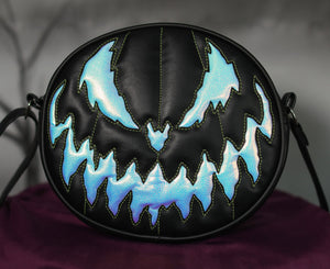 Zoom in of Bad Company pumpkin Black handbag with holographic textured vinyl pumpkin face with green stitching 