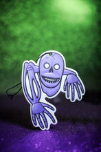 Load image into Gallery viewer, Purple skeleton car air freshener on green background.