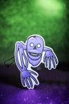 Purple skeleton car air freshener on green background.