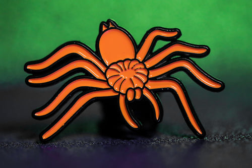 Enamel pin of orange spider.