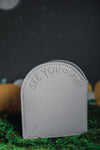 Back view of grey headstone wallet debossed with "see you soon"