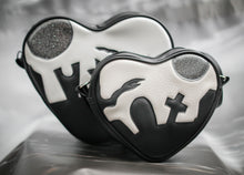 Load image into Gallery viewer, Heart shaped black and white bag with a graveyard silhouetted on a white sky with a grey glitter moon. 