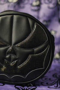 Black pumpkin with black glittery bat mouth on purple designed background.