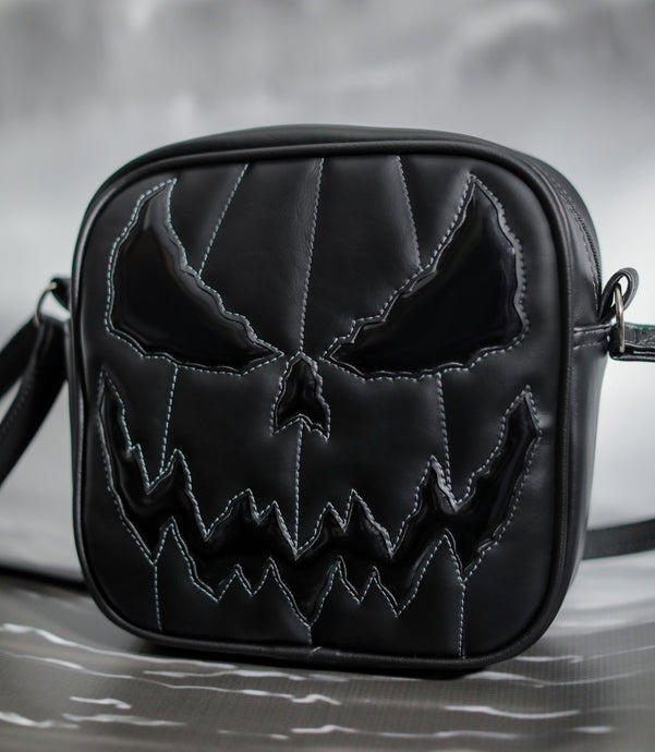 All black square bag with grey stitching on the face , Shiny patent black for the eyes and mouth with a plain black for he body