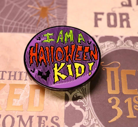 Round enamel pin that says "I am a Halloween kid!"