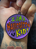 Hand holding keychain that says "I am a Halloween kid!"