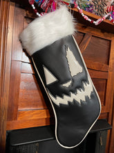 Load image into Gallery viewer, Black holiday stocking with white top, white glitter edging, and white jack-o-lantern face. 