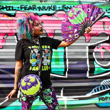 Load image into Gallery viewer, Girl hold purple fan with pumpkin face in front of graffiti wall.