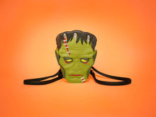 Load image into Gallery viewer, A stylized version of Frankenstein&#39;s Monster as a backpack against an orange background. 