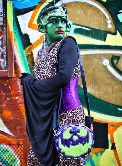 Girl dressed as monster wearing the monster bag, Glitter Purple and green glitter bag has black and white glitter pipping , green matching zipper